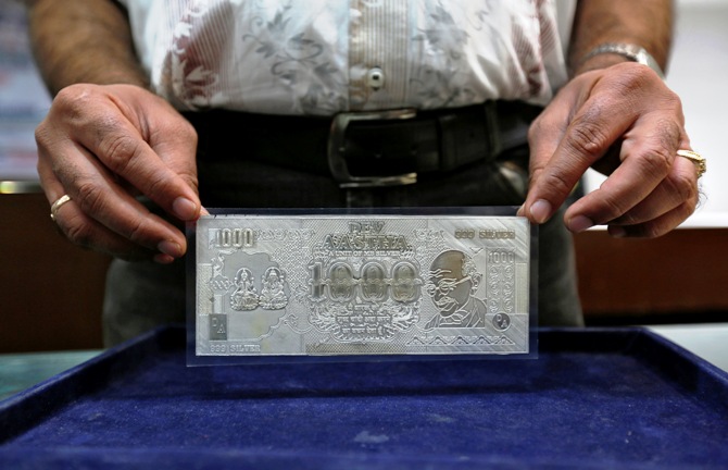 A jeweller poses with a silver plate in the form of an Indian rupee note inside a showroom in New Delhi.