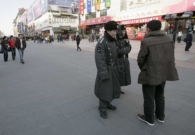 Security guards talk with a passer-by on Wangfujing street in Beijing, China.
