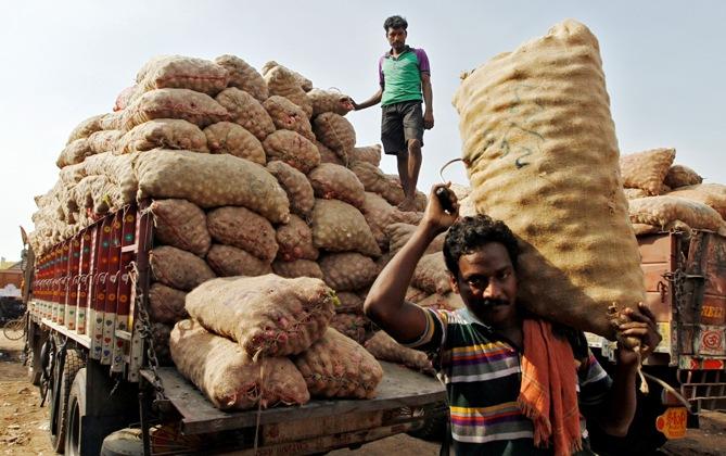 Labourers unload sacks filled with onions at a wholesale vegetable market in Chennai.