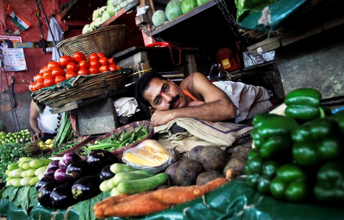  A vendor rests as he waits for customers at a vegetable market in Mumbai.