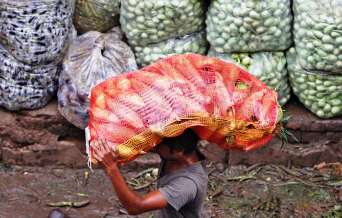 A man carries a sack filled with maize at a wholesale vegetable market in Ahmedabad.
