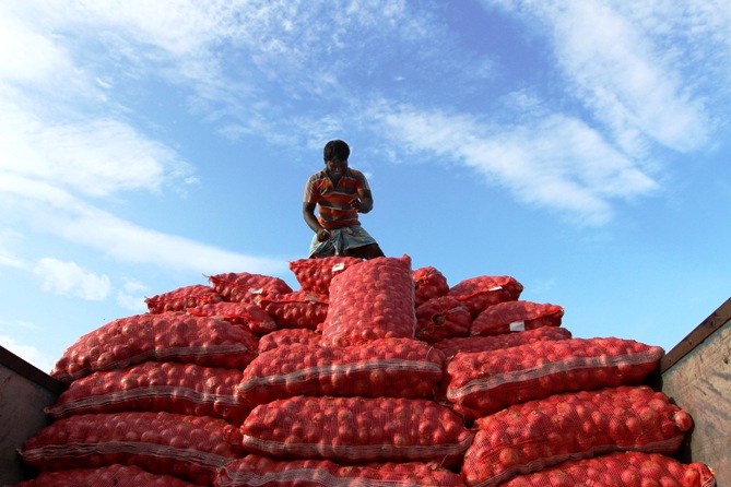 A labourer unloads sacks of onions from a supply truck at a vegetable wholesale market in Chennai. 