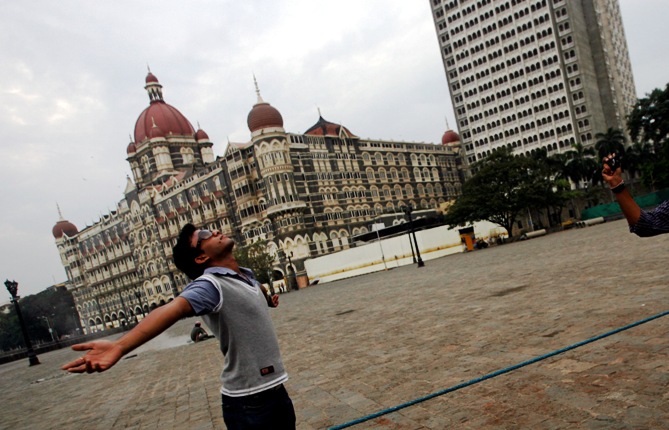 A visitor poses for a picture in front of Taj Mahal hotel in Mumbai.