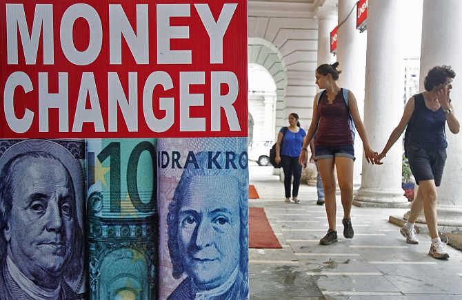 Tourists walk past a currency exchange shop at a shopping arcade in New Delhi.