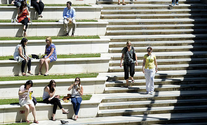 People sit in the sun in Sheldon Square in west London, United Kingdom.