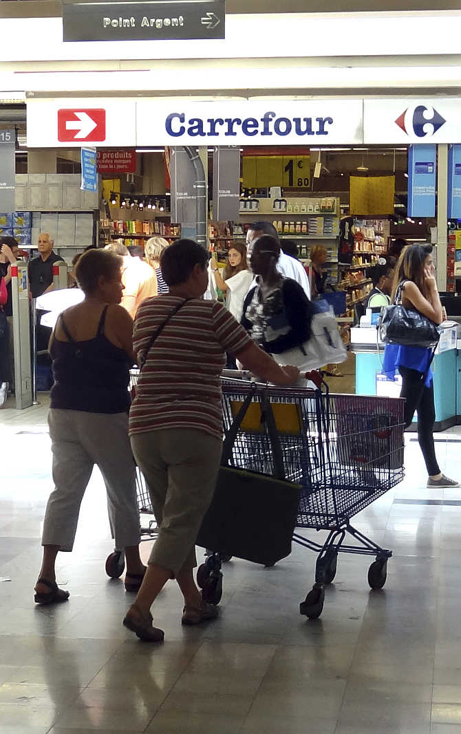 Customers push shopping trolley as they enter a Carrefour supermarket in Montreuil near Paris, France.