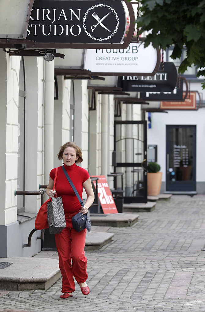 A woman holds a shopping bag as she walks past shops in Riga, Latvia.