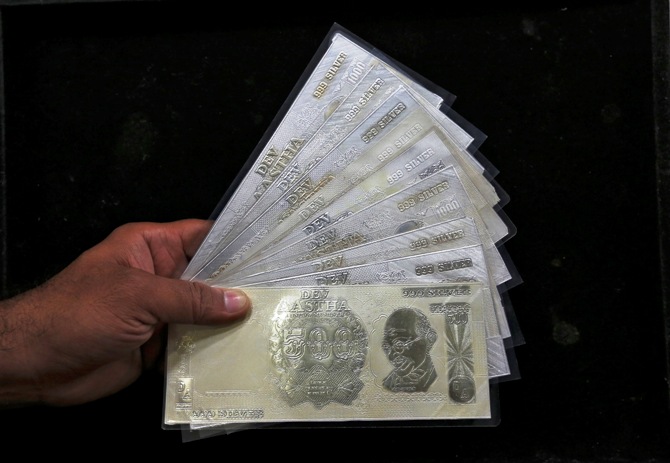 A jeweller poses with silver plates in the form of Indian rupee notes inside a showroom in New Delhi.