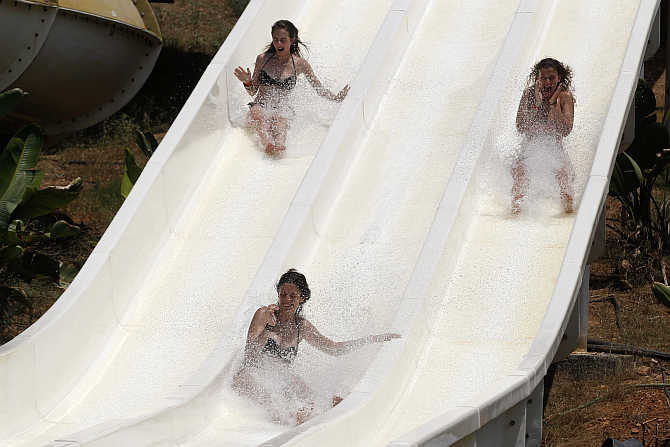 People enjoy a water slide at Copa Copana water park at Haidari suburb near Athens, Greece.