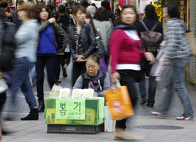 A vendor, selling traditional candies, waits for customers in Myeongdong shopping district in Seoul, South Korea.