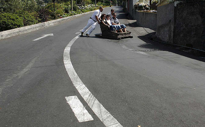 Carreiros (sledge drivers) push tourists in a sledge in Monte on the Atlantic island of Madeira, Portugal.