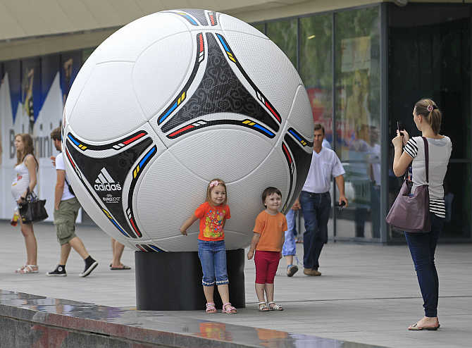 A woman takes photos of her children near a giant soccer ball outside of a shopping mall in central Donetsk, Ukraine.