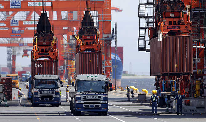 Workers load containers from trucks onto a cargo ship at a port in Tokyo, Japan.