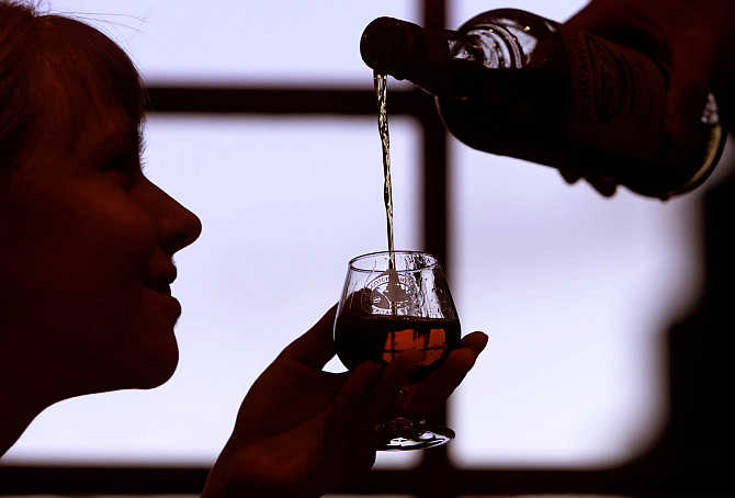 A woman extends her glass for whisky in Edinburgh, Scotland.