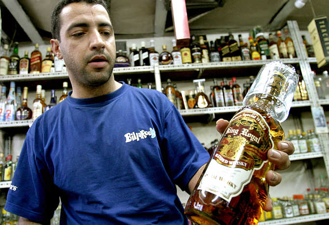 A vendor shows a bottle of whisky in a shop in Baghdad, Iraq.