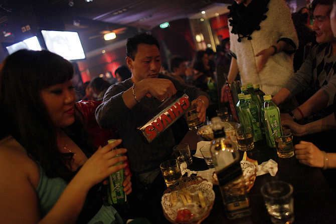A man pours whisky from a jug at a bar in a nightclub in Shanghai, China.
