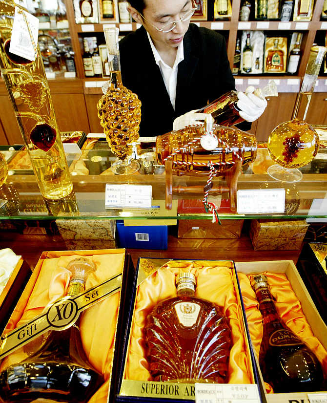 A salesman arranges a display of whisky bottles in a liquor shop.