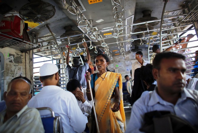 A blind woman begs for alms inside a commuter train during the evening rush hour in Mumbai.