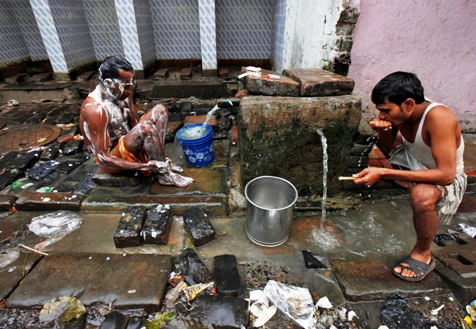 Men bathe at a roadside municipal tap in Kolkata.