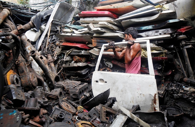 A labourer carries the door of a car inside a second-hand automobile parts market in Kolkata.