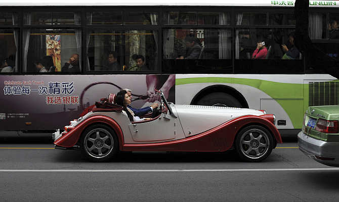 Charles Morgan and his wife Kiera drive a Morgan sport car during the opening of Morgan sport cars showroom in Shanghai, China.