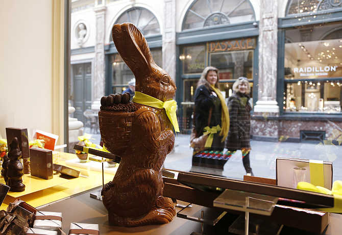 Two women walk past a chocolate Easter bunny at Belgian chocolate maker Neuhaus in Brussels, Belgium.