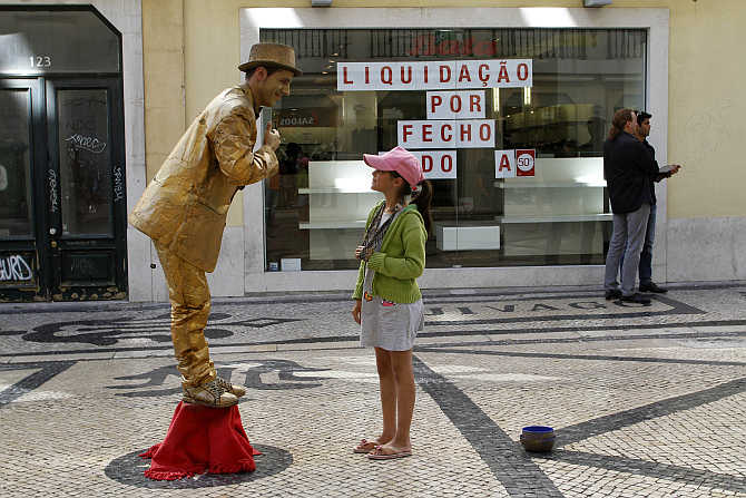 A girl looks at a performance artist in downtown Lisbon, Portugal.