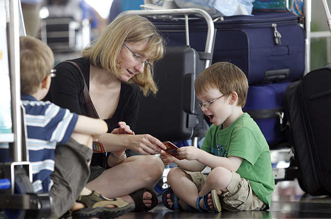 Lawrence Jones plays cards with his mother Susan Hourihan and brother Harvey as they wait for their flight to London, at Kuala Lumpur International Airport.