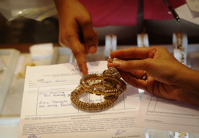 An employee explains the bill to a customer as gold bangles are placed on top of it inside a jewellery showroom in Mumbai.
