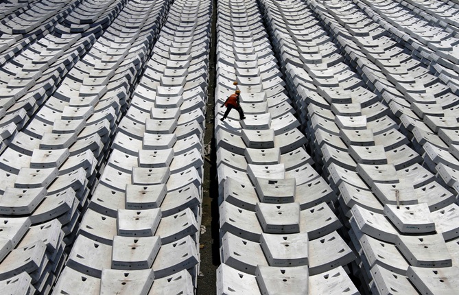 A worker walks over giant pieces of concrete that will be used to make tunnels for the metro railway, at a casting yard in Chennai.