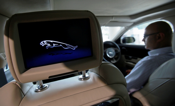 A man sits inside a Jaguar vehicle as he demonstrates its features at a Jaguar Land Rover showroom in Mumbai.