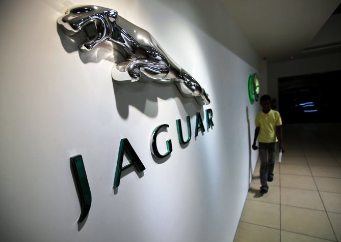 A showroom attendant walks past company logos at a Jaguar Land Rover showroom in Mumbai.