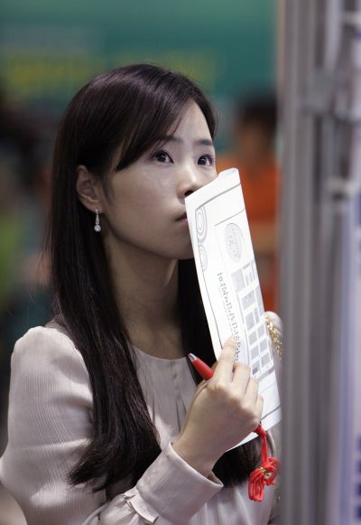 A woman looks at job adverts at a job fair.