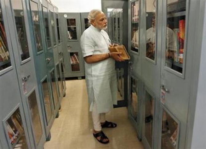 Modi looks at books in a library inside his residence.