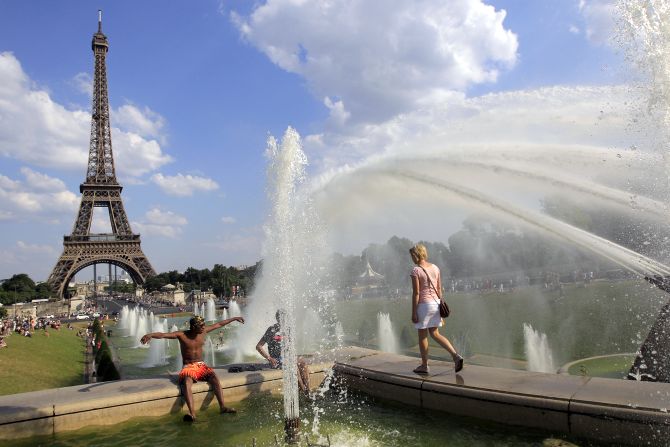People cool off in a fountain of the Trocadero Square in front of the Eiffel Tower on a warm summer afternoon in Paris.