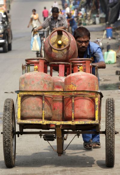 An employee of a cooking gas agency pushes a rickshaw loaded with gas cylinders in Mumba.