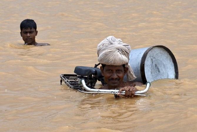 A flood-affected man with his bicycle moves to a safer place after the rise in the water levels of the river Ganges at Maner in Bihar. 