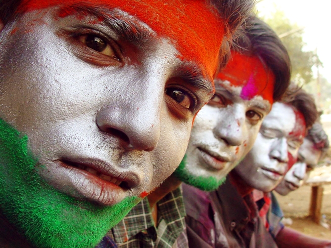 Indians sit with their faces painted with the colours of the Indian national flag as they celebrate Holi in Bhopal.