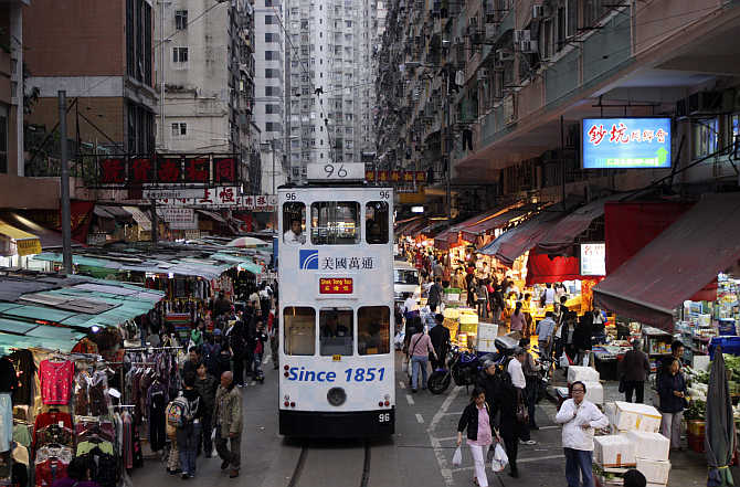 A tram passes by a marketplace in downtown Hong Kong.