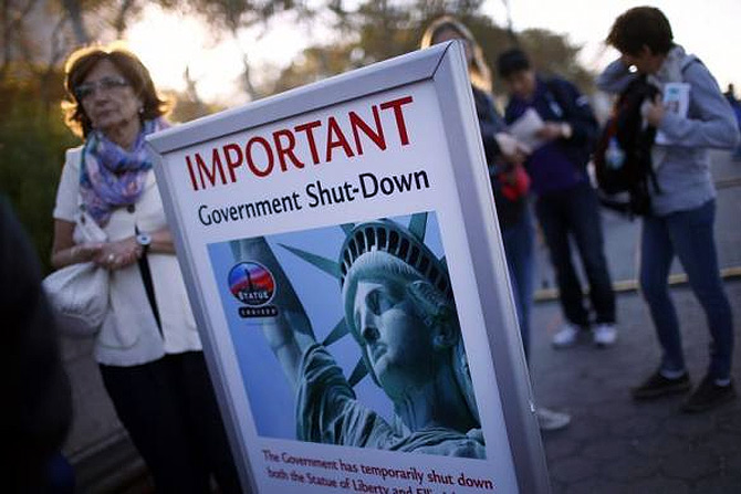 Tourists stand next to a sign announcing the closure of the Statue of Liberty, a US National Park, due to the US Government shutdown near the ferry dock to the Statue of Liberty in Battery Park in New York.