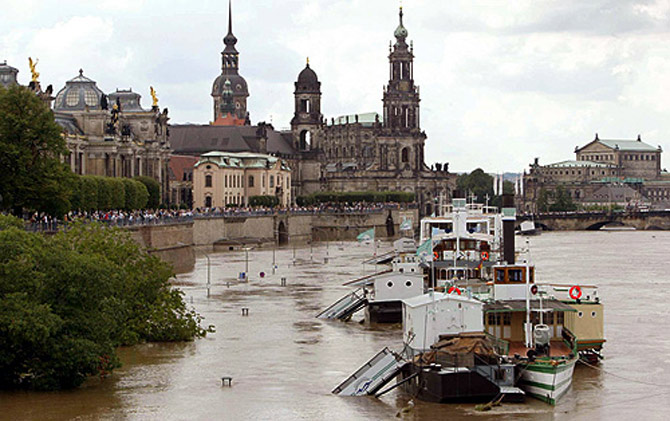 Boats are seen floating above the piers on a flooded street in front of the historic skyline of Dresden, along the banks of the river Elbe.