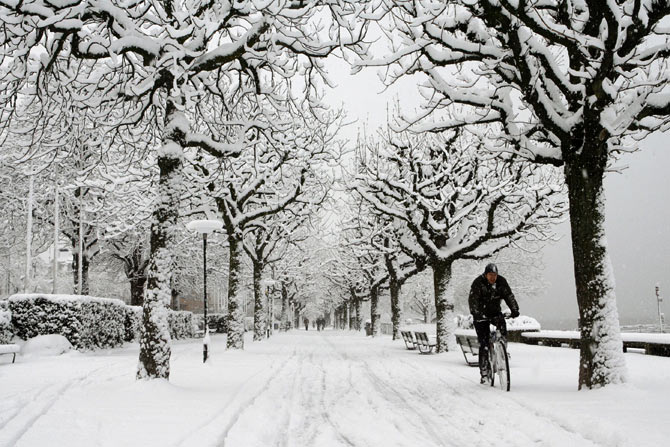 A man cycles during snowfall in Zurich.