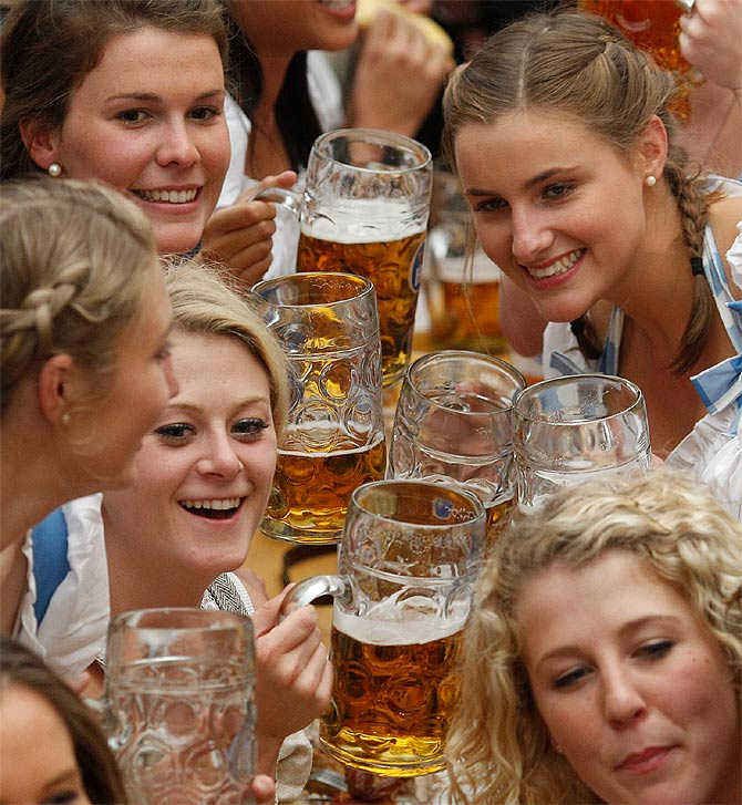People wearing traditional Bavarian clothes toast with beer at the Oktoberfest in Munich, Germany.