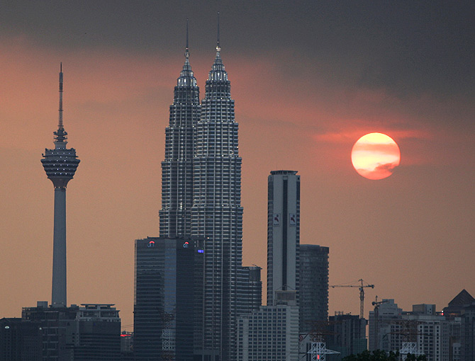 The sun sets near the Petronas Twin Towers (C) and Kuala Lumpur Tower (L).