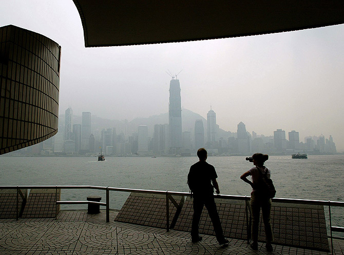 Tourists look out over Victoria harbor and the central business district.