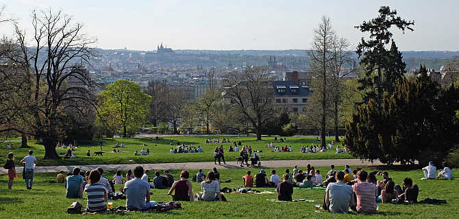 People relax in a park during a warm spring day in Prague.