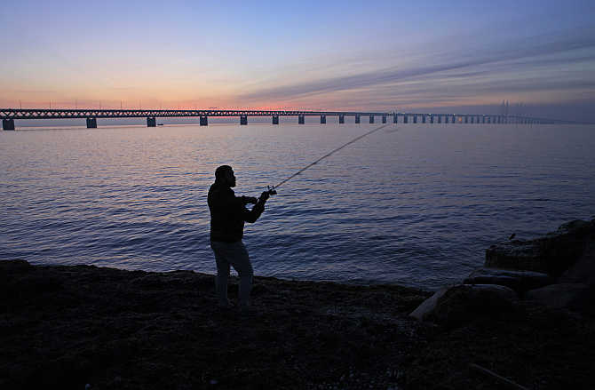 A man fishes near the Oresund bridge, which links the city of Malmo in Sweden to Copenhagen, the capital of Denmark, and has a total length of 7,845 metres.