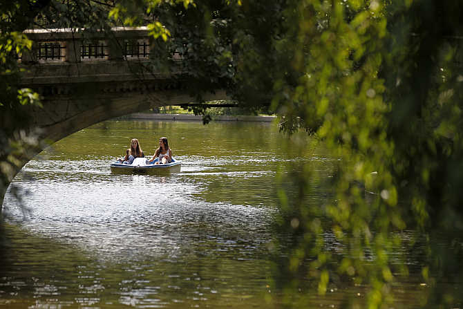 Two girls ride a water bicycle in a park in Bucharest as temperature reached 36 degrees Celsius in southern Romania.
