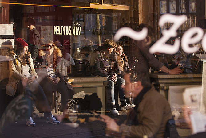 Visitors of a local cafe are reflected in a window in Amsterdam, the Netherlands.