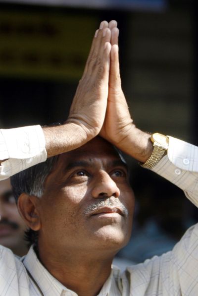 An investor gestures with folded hands towards the Bombay Stock Exchange (BSE) building.
